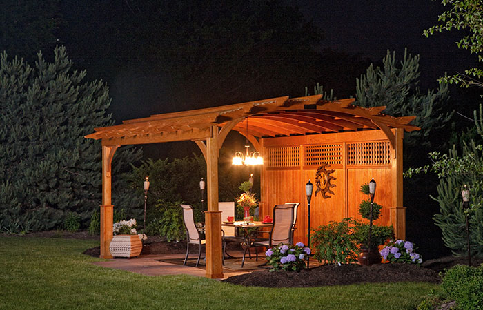 cedar pergola with large arch and exterior lighting