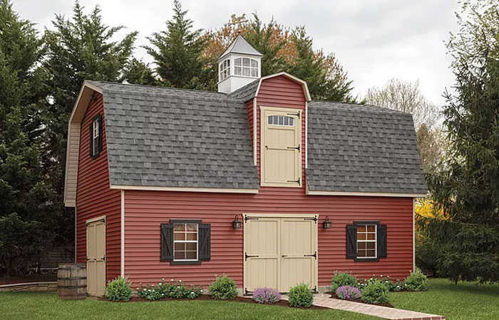 two story shed with gambrel roof and cream colored loft door